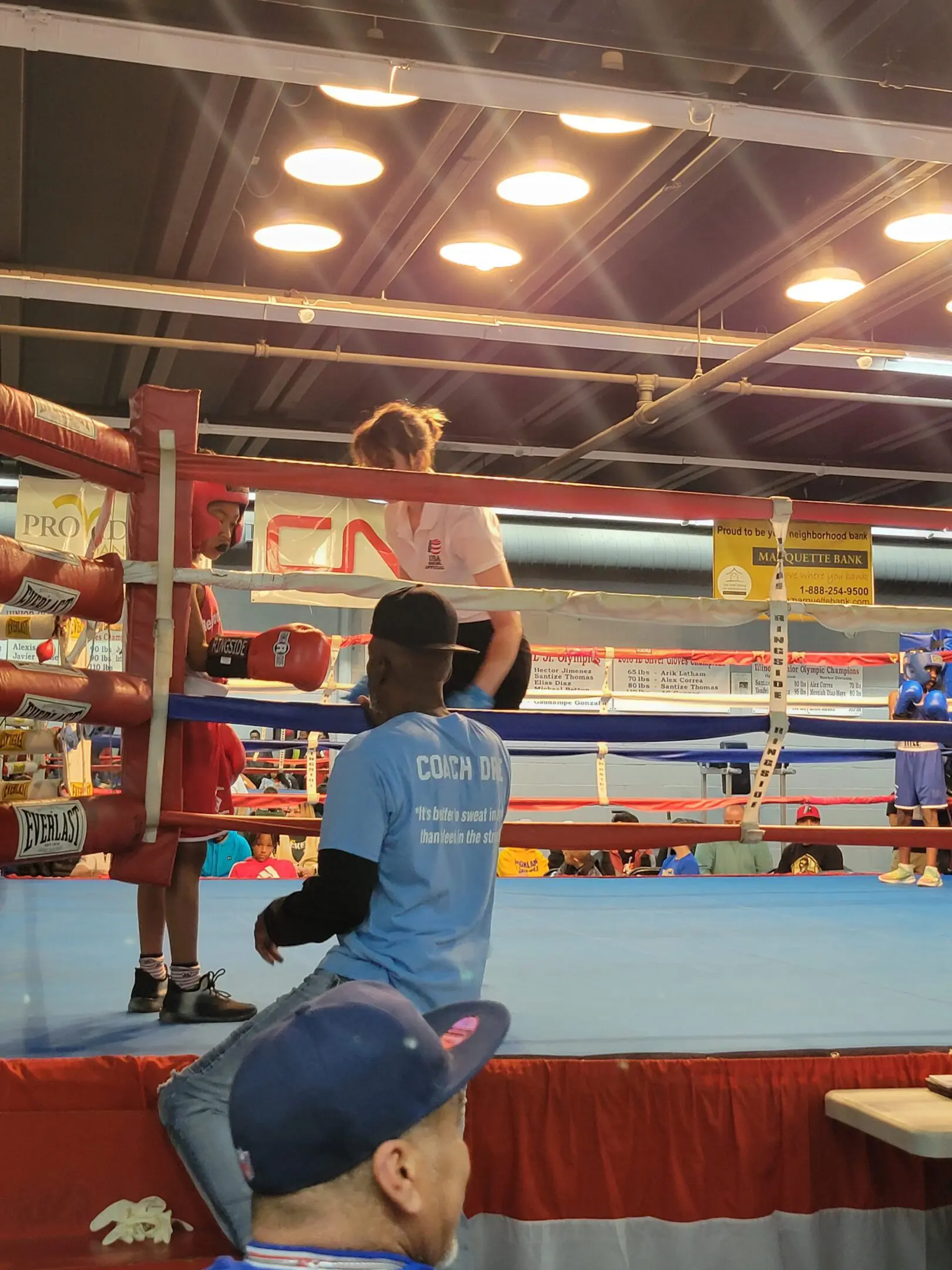 A boxer celebrates victory in the ring with arms raised.